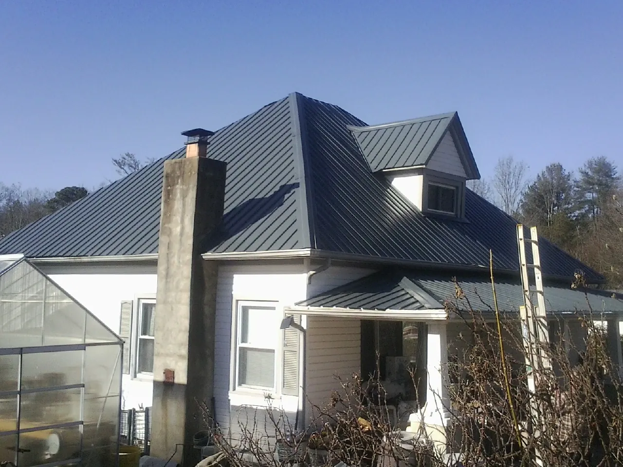 Dark blue standing seam metal roof on a white farmhouse with dormer — Slate & Tile Roof Repair by Roofing Brothers in Menan