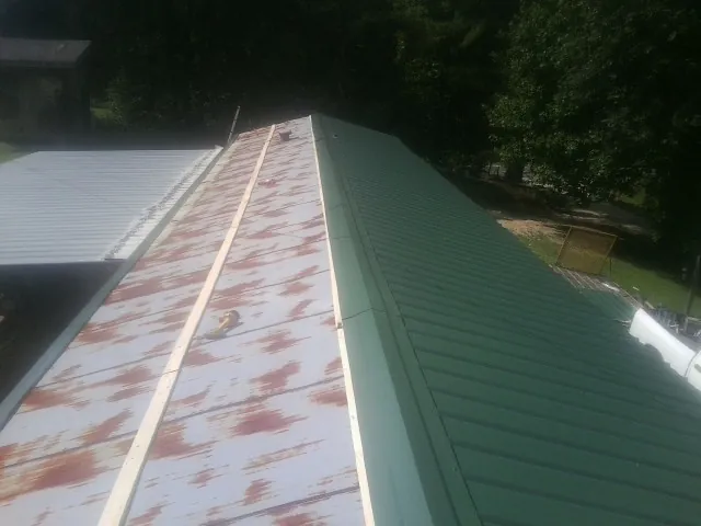Old rusted panels beside newly installed green metal roofing — Wind Damage Roof Repair by Roofing Brothers in Menan