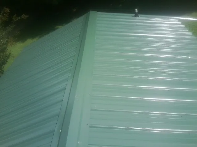 New green metal panels meeting at the ridge of a roof — Flat Roof Repair work by our crew in Menan