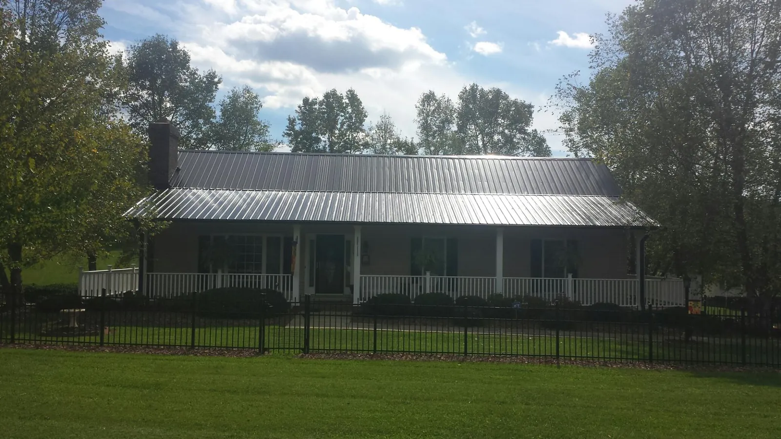 Gray metal roof on a brick ranch with a full width front porch — Gutter Guard Installation work by our crew in Menan