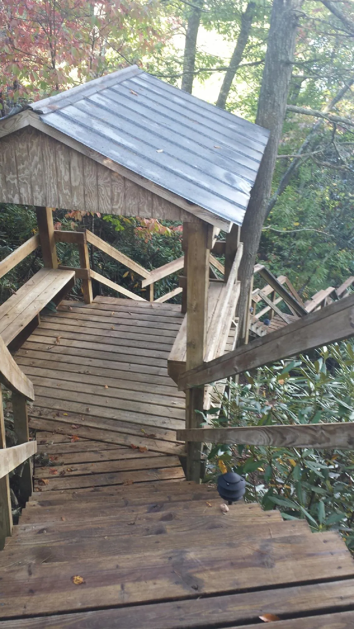 Metal roofed shelter over wooden steps on a wooded walkway — Skylight Repair & Installation work by our crew in Menan
