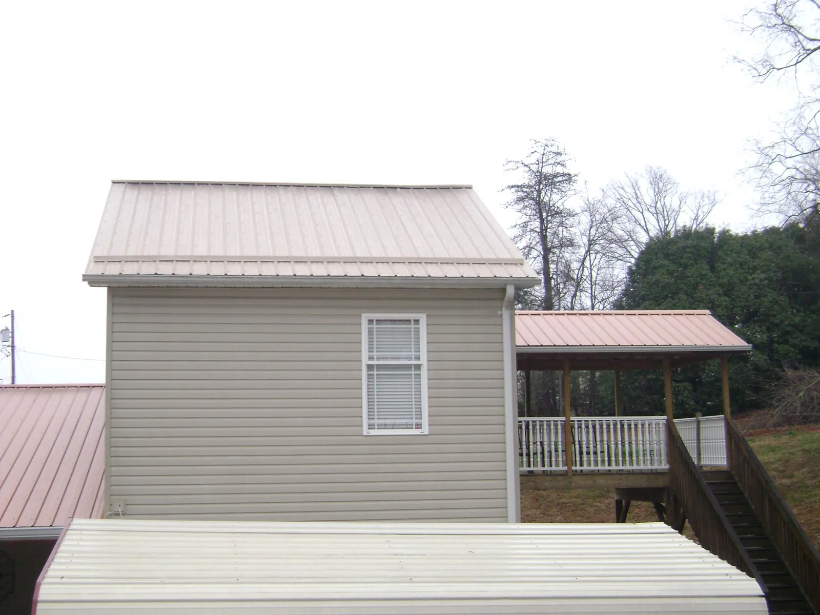 Tan metal roofs on a two story addition and attached porch, from a Roof Replacement job in Menan