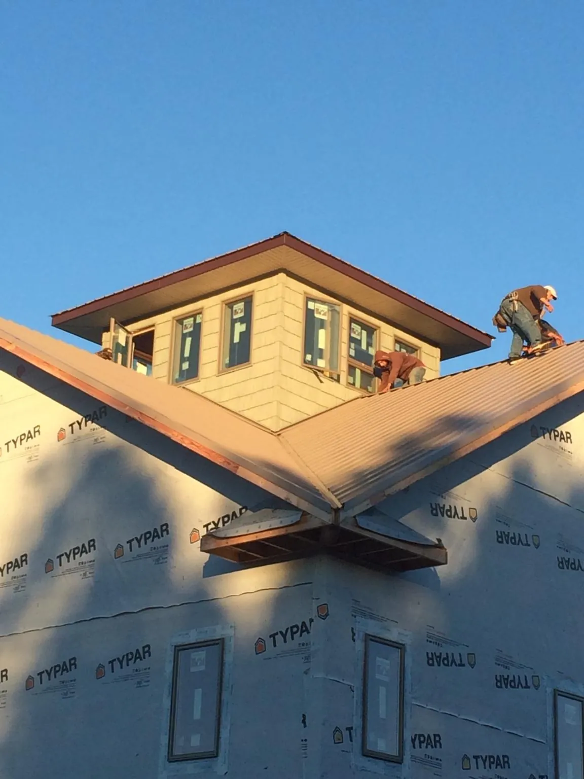 Roofers working around a rooftop cupola on a new metal roof at sunset — Roof Waterproofing in Menan by Roofing Brothers